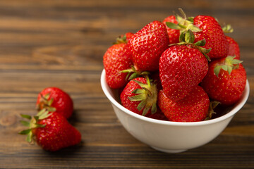 Fresh ripe strawberries in a bowl on a brown texture background.Vegetarian organic berry.Healthy food.Copy space.Place for text