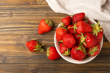 Fresh ripe strawberries in a bowl on a brown texture background.Vegetarian organic berry.Healthy food.Copy space.Place for text