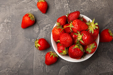 Fresh ripe strawberries in a plate on a black texture background.Vegetarian organic berry.Healthy food.Vitamins.Copy space.Place for text