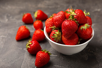 Fresh ripe strawberries in a plate on a black texture background.Vegetarian organic berry.Healthy food.Vitamins.Copy space.Place for text