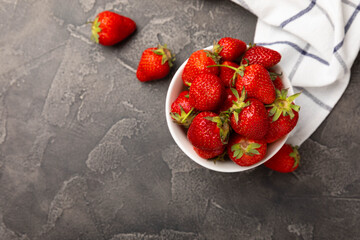 Fresh ripe strawberries in a plate on a black texture background.Vegetarian organic berry.Healthy food.Vitamins.Copy space.Place for text