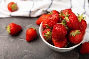 Fresh ripe strawberries in a plate on a black texture background.Vegetarian organic berry.Healthy food.Vitamins.Copy space.Place for text