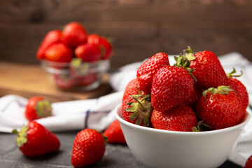 Fresh ripe strawberries in a plate on a black texture background.Vegetarian organic berry.Healthy food.Vitamins.Copy space.Place for text