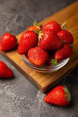 Fresh ripe strawberries in a plate on a black texture background.Vegetarian organic berry.Healthy food.Vitamins.Copy space.Place for text