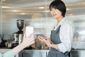 カフェ スタッフにスマートフォンを見せる女性