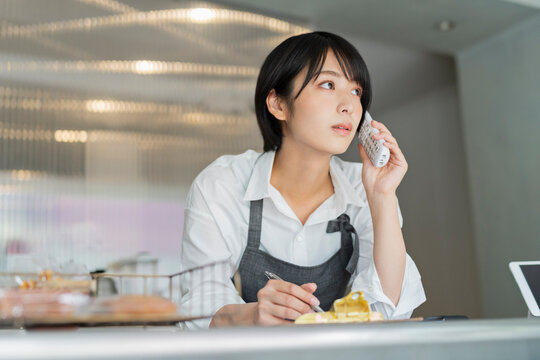 カフェ 電話をする女性スタッフ