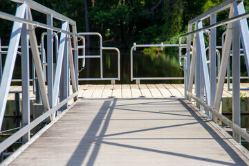 a T shaped dock with a silver metal hand rail on the still waters of the lake surrounded by lush...