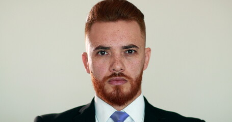 Portrait of handsome redhair man wearing business suit looking at camera, no expression, emotionless