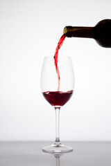 Fototapeta na wymiar Red wine pouring into a glass from bottle isolated on white background