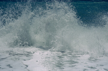 Blue waves crashing on the beach with white spray and foam. Dangerous stormy sea. Beautiful textured coastline background. 