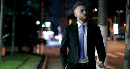 Pensive worried business man walking at night in city