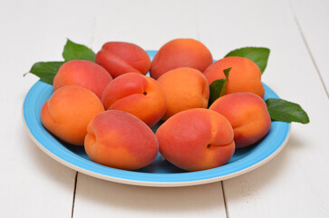 ripe fresh apricots on a blue plate close-up