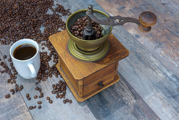 Wooden surface with a manual coffee grinder and a cup of coffee - Powered by Adobe