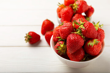 Fresh ripe strawberries in a plate on a white wooden background.Vegetarian organic berry.Healthy food.Vitamins.Copy space.Space for text