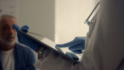 Woman doctor collecting medical history senior patient using tablet close up.