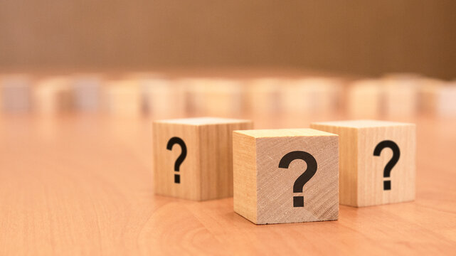 three cubes with question mark on wooden background. space for text