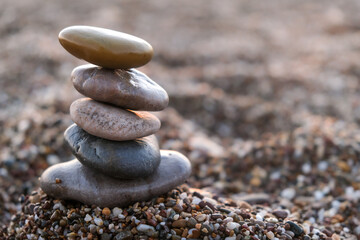 Fototapeta na wymiar Selective Focus, Pyramid of pebbles on the beach. Concept of zen, stability, harmony, balance and meditation.