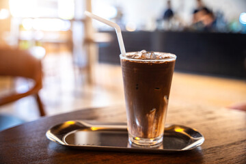 Close-up of cocoa ice  in cup mug on glass in wood desk in coffee shop at the cafe in garden,during business work concept