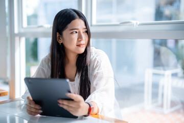 asian freelance people business female wearing smartwatch talking making using casual working with tablet for browsing internet, chatting and blogging and smartphone,notebook in coffee shop.