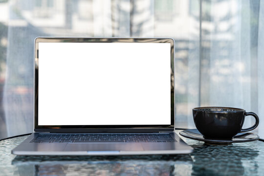 Mockup of laptop computer with empty screen with coffee cup and smartphone on table of the coffee shop outdoor background,White screen