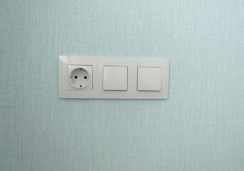 isolated white beige switch and socket on a light wall. aesthetics of electrics, repair, security, interior, design. place for text