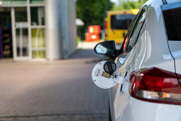 Parked white modern car on gas station with empty and opened gas tank waiting for refueling. View...