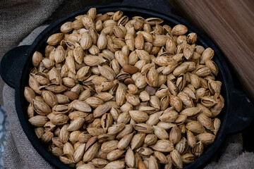 large unpeeled unroasted almonds lie in a black metal frying pan