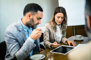 Colleagues at meeting in boardroom, sitting at table together, sharing ideas, discussing project strategy.