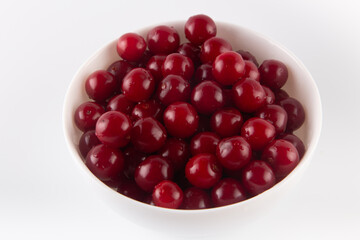 Heap of red wet sweet cherry in plate close up on a white background