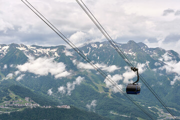 Cabin of gondola cable car type 3S going up among snow-capped mountain peaks, natural landscape.