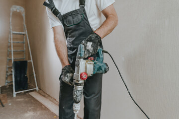 Builder in work overalls plastering a wall indoor