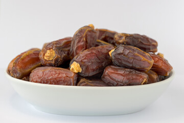 Heap of dates, pile of delicious dried dates in white bowl isolated on white background. Arabian food.