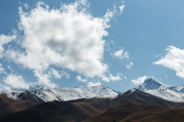 White cloud over the mountains. Blue sky and snowy mountains.
