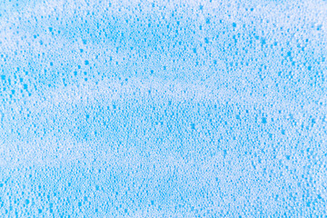 Fototapeta na wymiar White cosmetics foam texture on blue backdrop. Cleanser, soap, shampoo bubbles. Foamy skin care product sample. Skincare, cosmetology and beauty concept