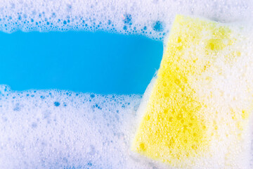 Cleaning yellow sponge and a soapy bubble foam on a blue background. Cleaning concept, cleaning...