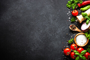 Food background on black stone table. Fresh vegetables, herbs and spices. Ingredients for cooking with copy space.