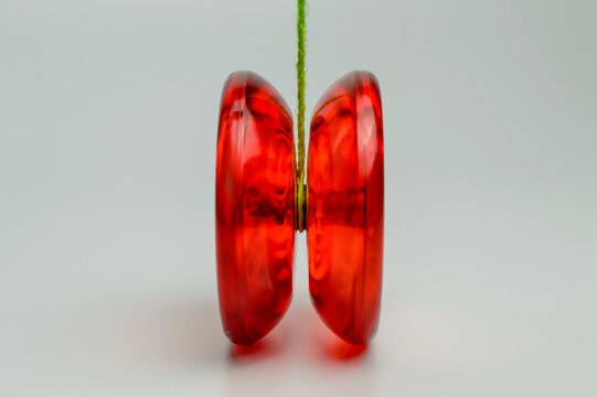 Red plastic yo-yo toy isolated on White Background with green rope attached to it.