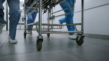 Medics legs running down hospital corridor rolling gurney to emergency room.