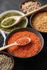 Overhead view of bowls of assorted raw legumes on a dark wooden table