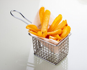 French fries in metal wire basket isolated on a white background