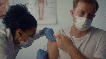 Woman medic injecting covid vaccine in man shoulder. Physician using syringe.