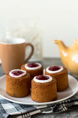 Cakes on a white plate. On the table is a cup, a kettle