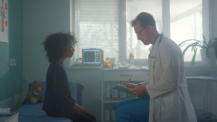 Obraz premium Teen girl sitting consulted with pediatrician in clinic. Child talking physician