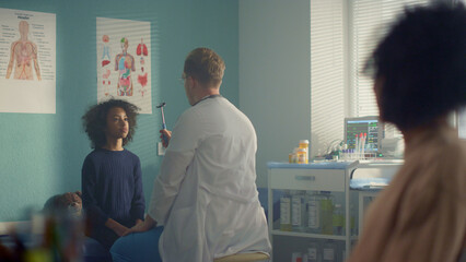 Obraz premium Pediatrician checking preteen girl visual reflex using neurological hammer.