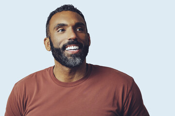headshot portrait of a handsome bearded mid adult man smiling looking away at copy space against gray background studio shot