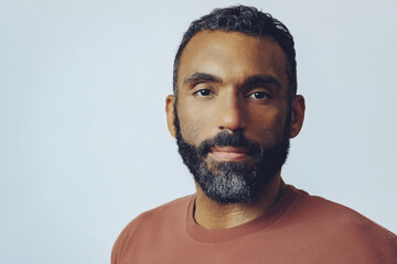 headshot portrait of a handsome thoughtful bearded mid adult man looking at camera against gray background studio shot