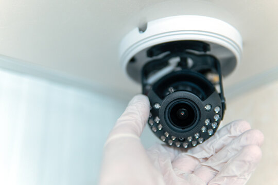 Close-up Of The Installation Of A Surveillance Camera, A Male Hand In A White Glove Holds A Surveillance Camera.