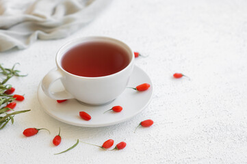 Cup of herbal goji berry tea with fresh goji berries on rustic table