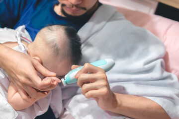 Father cutting my baby's nails with electic nail clipper while baby sleep.