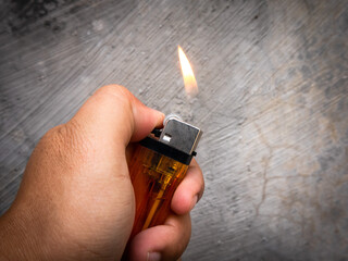a man manages to light a gas lighter against a rough gray wall background - obrazy, fototapety, plakaty